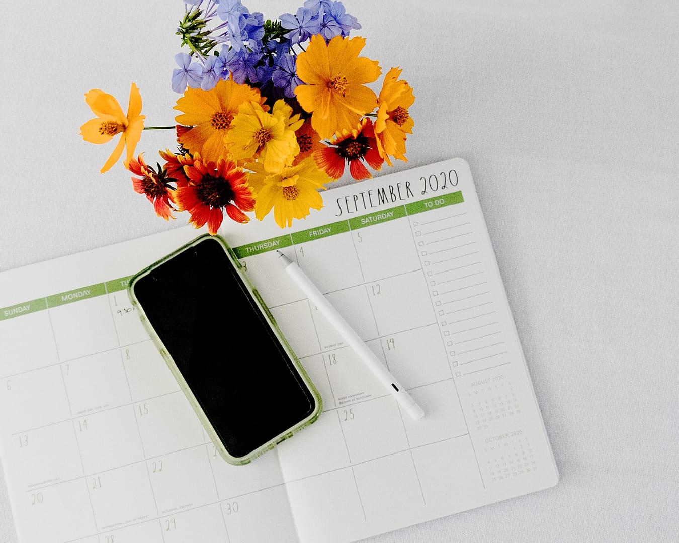 managing your time - phone on calendar next to flowers